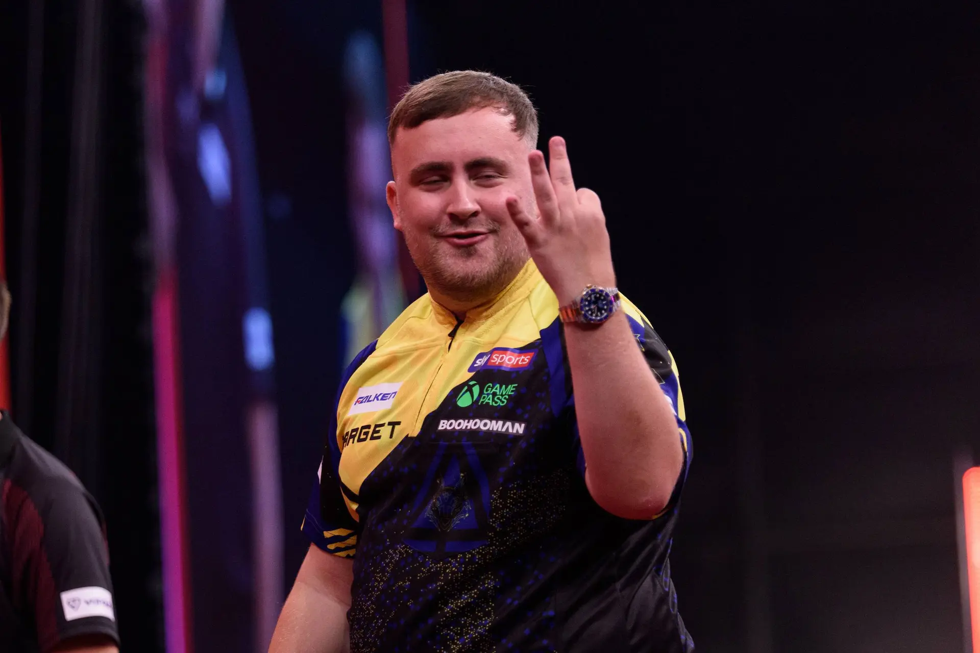 Luke Littler steekt een aantal vingers op.