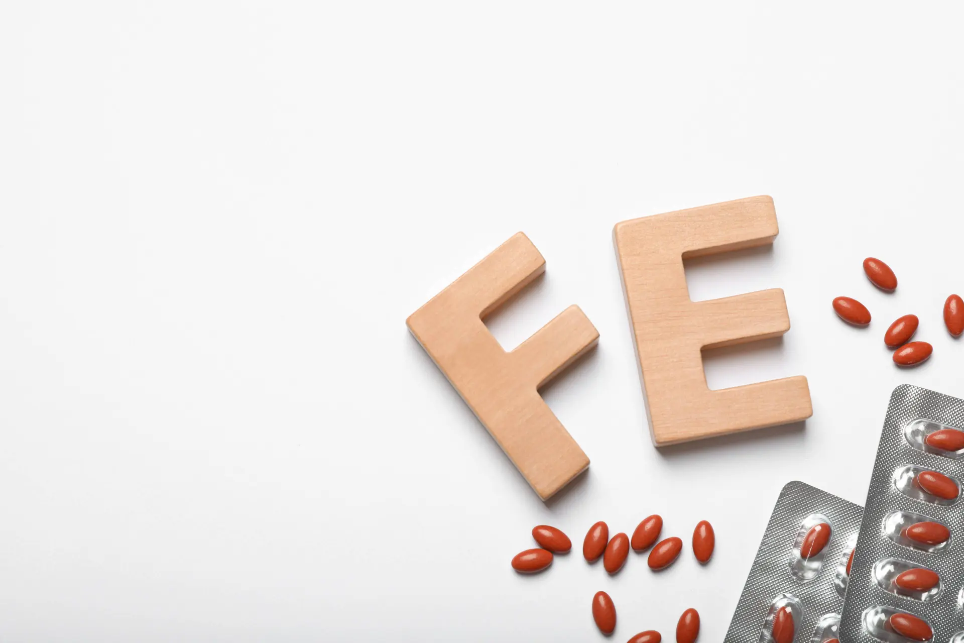 letters FE on white background next to iron tablets