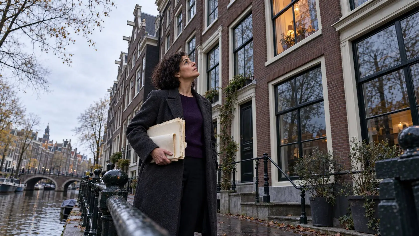 Een vrouw van rond de 48 staat met oude papieren in haar hand voor een Amsterdams appartementengebouw en kijkt omhoog.