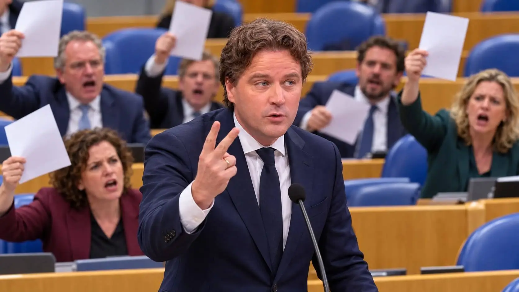 Bontenbal steekt twee vingers op in de Tweede Kamer, achter hem Kamerleden die boos papieren omhoog houden
