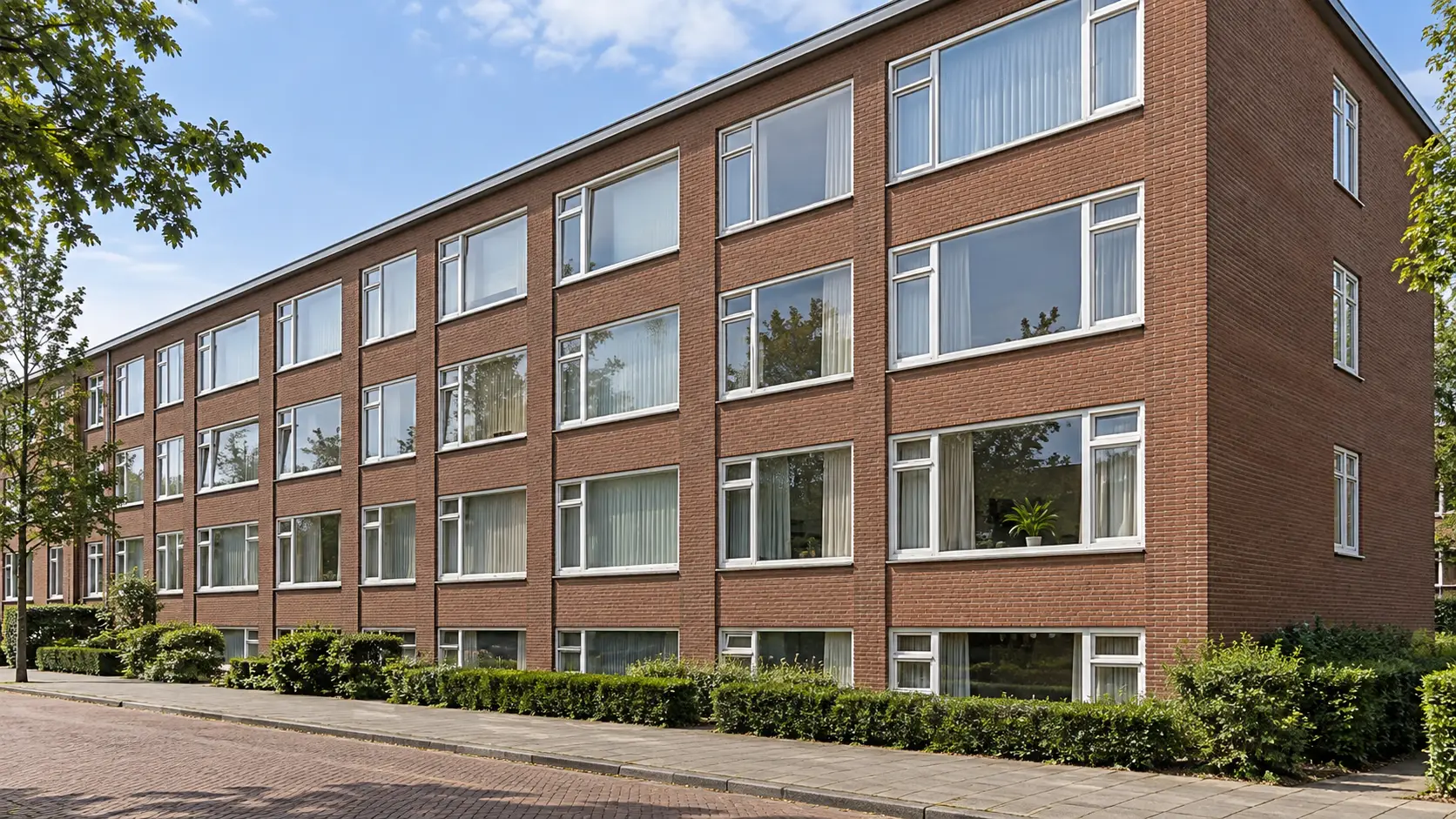 Bakstenen appartementencomplex met grote ramen en zonder balkons.