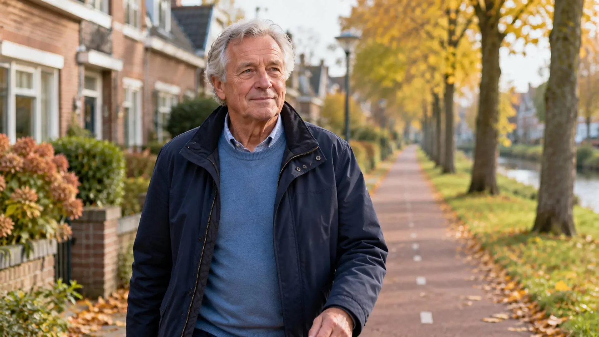 Een oudere man die op een herfstdag door een Nederlandse woonwijk wandelt.