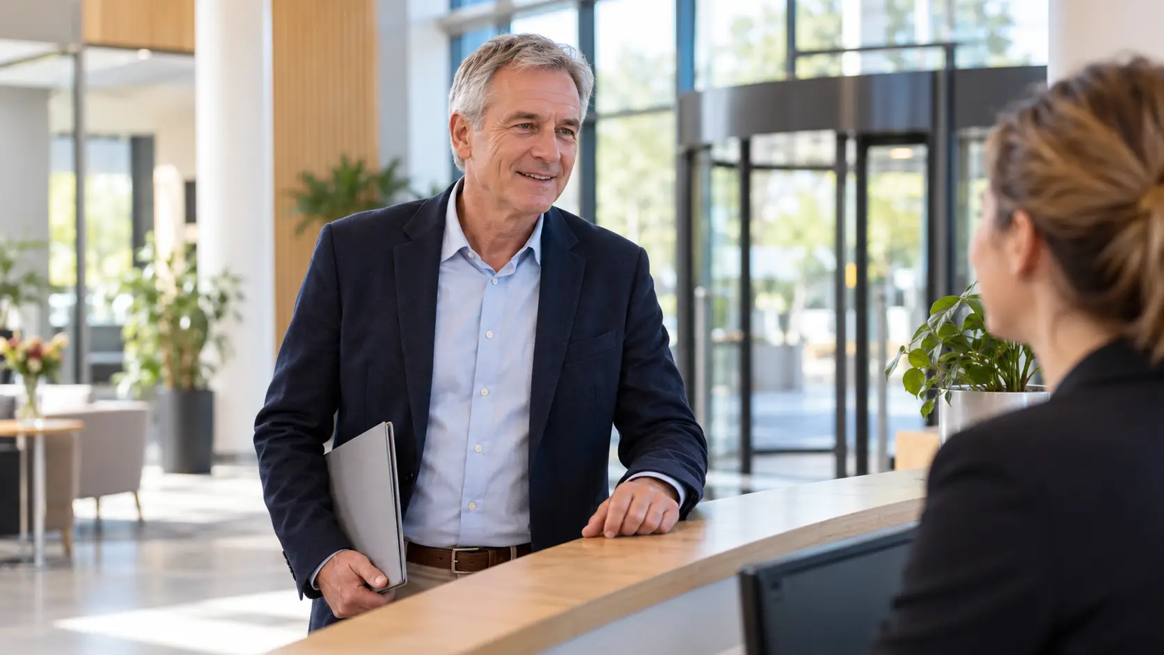 Man met een dunne map meldt zich bij de receptie van een bedrijf voor een sollicitatiegesprek.