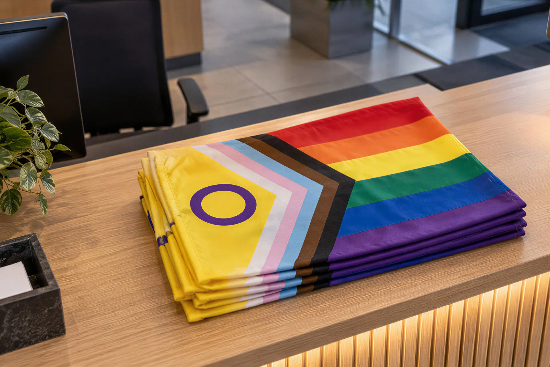 Illustratie van gevouwen intersekse-progressvlaggen op een gemeentelijke ontvangstbalie.