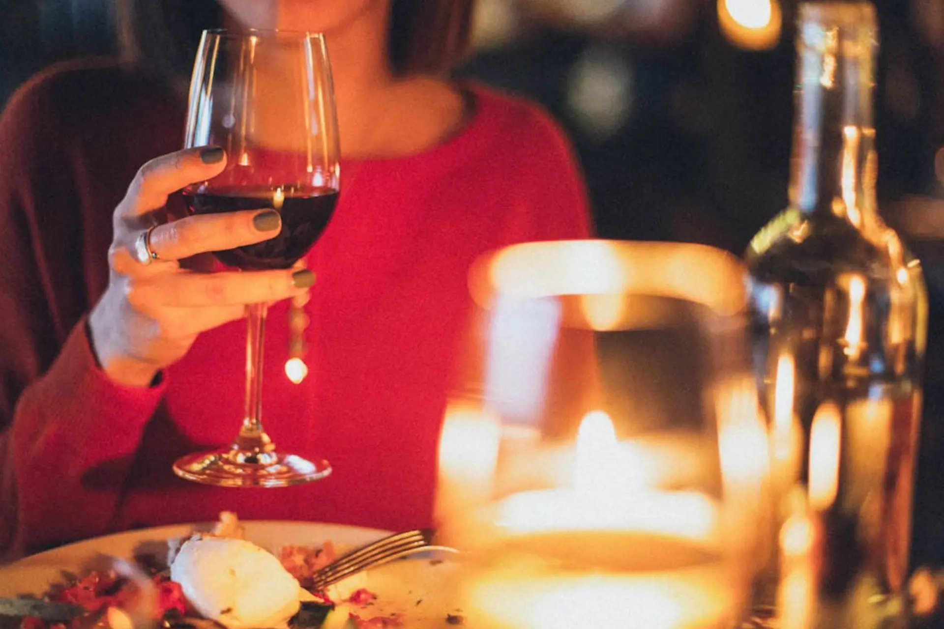 een vrouw met een glas wijn aan tafel