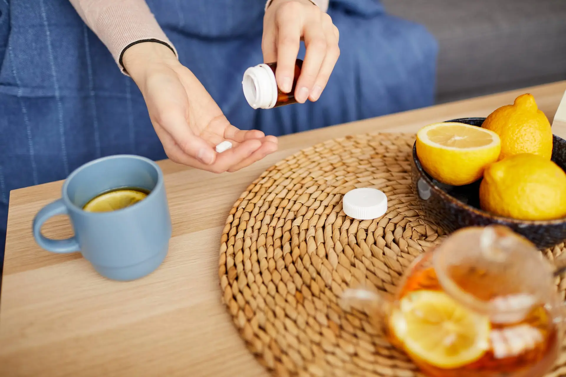 Close-up van de vrouw die vitamines neemt en thee drinkt met citroen thuis