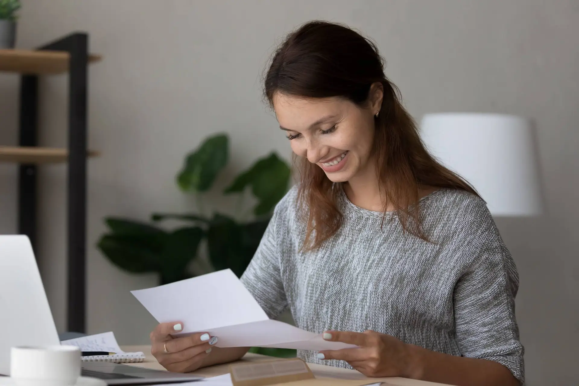 Een vrouw leest aan de keukentafel een brief van haar verhuurder.
