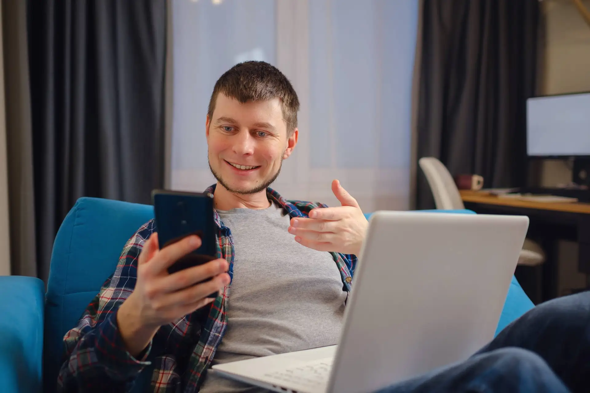 Een man zit ’s avonds alleen op de bank en chat op zijn telefoon.