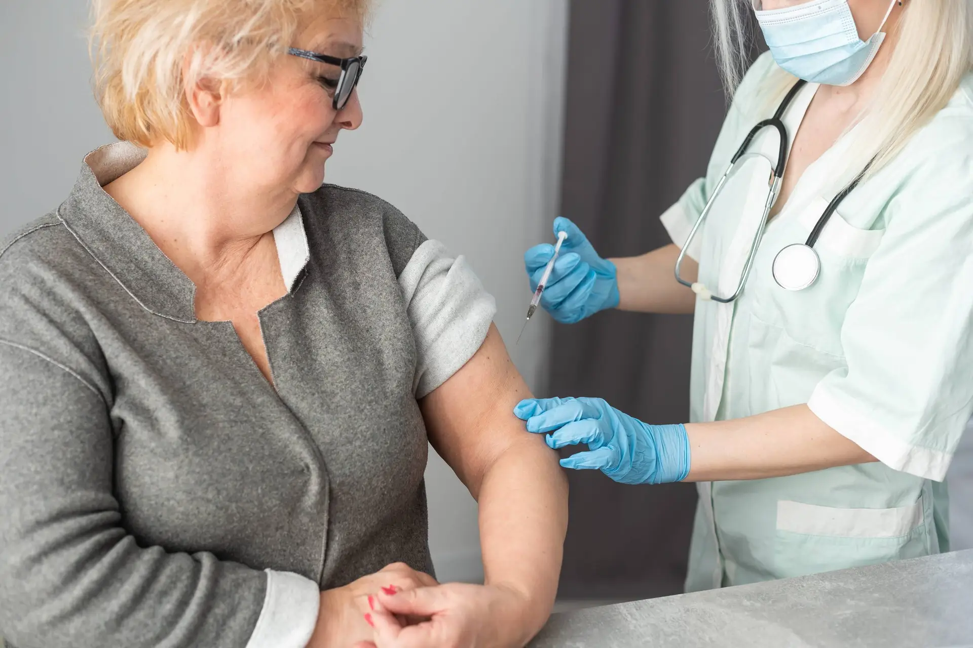 Close-up verpleegkundige die vaccininjectie doet aan oudere vrouw.
