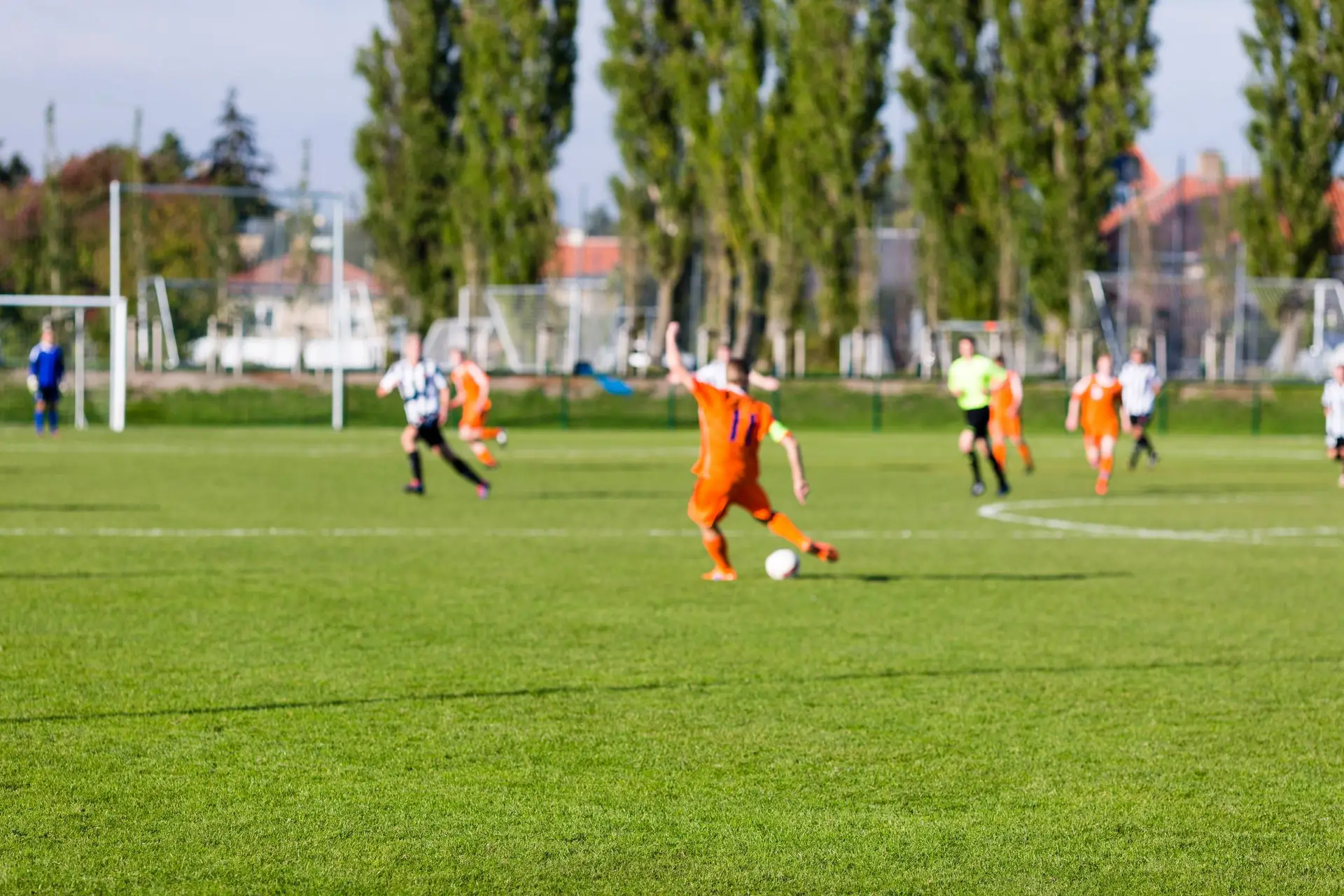 Amateurvoetballers strijden om de bal op een kunstgrasveld van een dorpsclub.