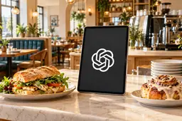 Tablet met het OpenAI-symbool tussen een sandwich en een kaneelbroodje op de balie van een licht restaurant.