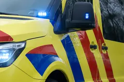 Detail van een gele ambulance met rood-blauwe strepen en blauwe zwaailichten