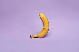 Een man slikt een banaan verpakt in een condoom door