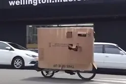 Fietser gaat door de regen in een enorme kartonnen doos