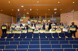 Groepsfoto met donatiecheques in het auditorium