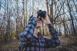 young-woman-using-binoculars-forest