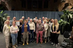 Vrijwilligers Alzheimer Café Lingewaard zijn superblij met VVD-zorgprijs.Theo Aaldering overhandigde het bijbehorende beeldje twee mensen die elkaar aankijken met een hart ertussen