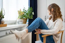 full-shot-woman-sitting-near-heater