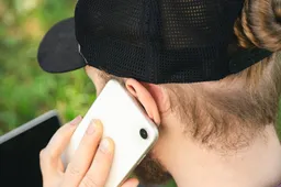 man-is-talking-smartphone-while-sitting-grass-with-laptop