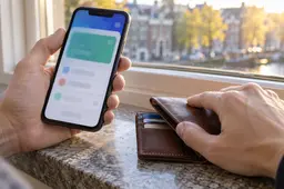 Spaarder gebruikt een bankapp op een smartphone naast een leren portemonnee.