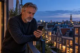 Man op een balkon kijkt twijfelend naar zijn telefoon in de avond