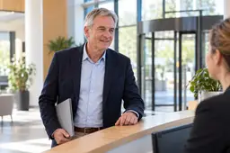 Man met een dunne map meldt zich bij de receptie van een bedrijf voor een sollicitatiegesprek.