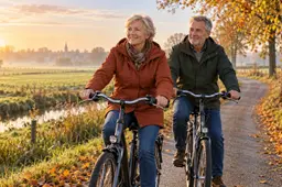 Stel van begin zestig fietst op een doordeweekse herfstochtend over een landweggetje