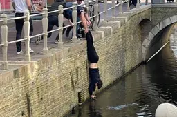 Duif uit gracht Leeuwarden gehaald door redder die acrobatische toeren uithaalt