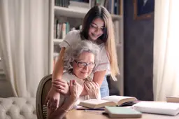 oma_bejaarde_kleindkind_meisje_knuffel_tafel_boeken_lezen