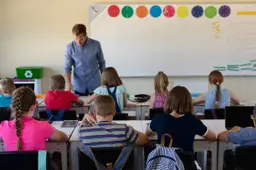 Een leraar geeft les voor een klas met leerlingen aan hun tafels