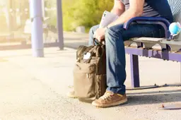 Groene reis rugzak, hoed, kaarten, glazen op het busstation