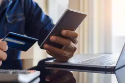 Iemand houdt een bankpas tegen de achterkant van een smartphone.