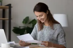 Een vrouw leest aan de keukentafel een brief van haar verhuurder.