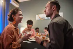 Twee mensen praten met elkaar op een feestje, de een luistert aandachtig naar de ander.