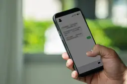 close-up van een duim boven een sms met een link op een smartphonescherm