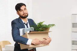 Werknemer die met een doos spullen het gebouw verlaat.