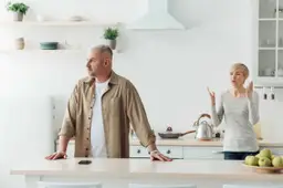 Een man en een vrouw zitten aan de keukentafel en praten na een ruzie.