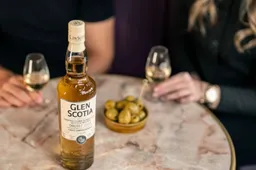 Glen Scotia Double Cask Bordeaux Wine Finish whiosky  op tafel bij vrouwen met glas erbij