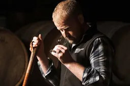 Adam Hannett Bruichladich Distillery Octomore Farm met een Tulip Glass naast whiskyvaten