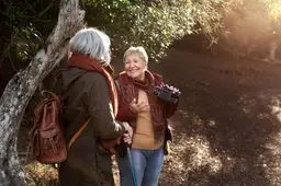 two-senior-female-friends-enjoying-hike-nature-while-using-binoculars