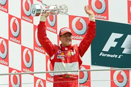 Michael Schumacher signeert met behulp van zijn vrouw de helm van oud-kampioen Stewart