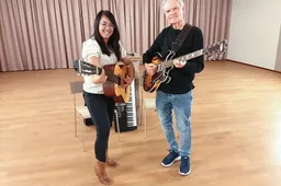 Lenna en Wim staand met gitaren kijken naar de camera