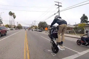 Stuntende waaghals op motor maakt schuiver op het asfalt