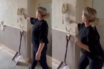 Vrouw ramt wel even een oude telefoon van de muur met een hamer