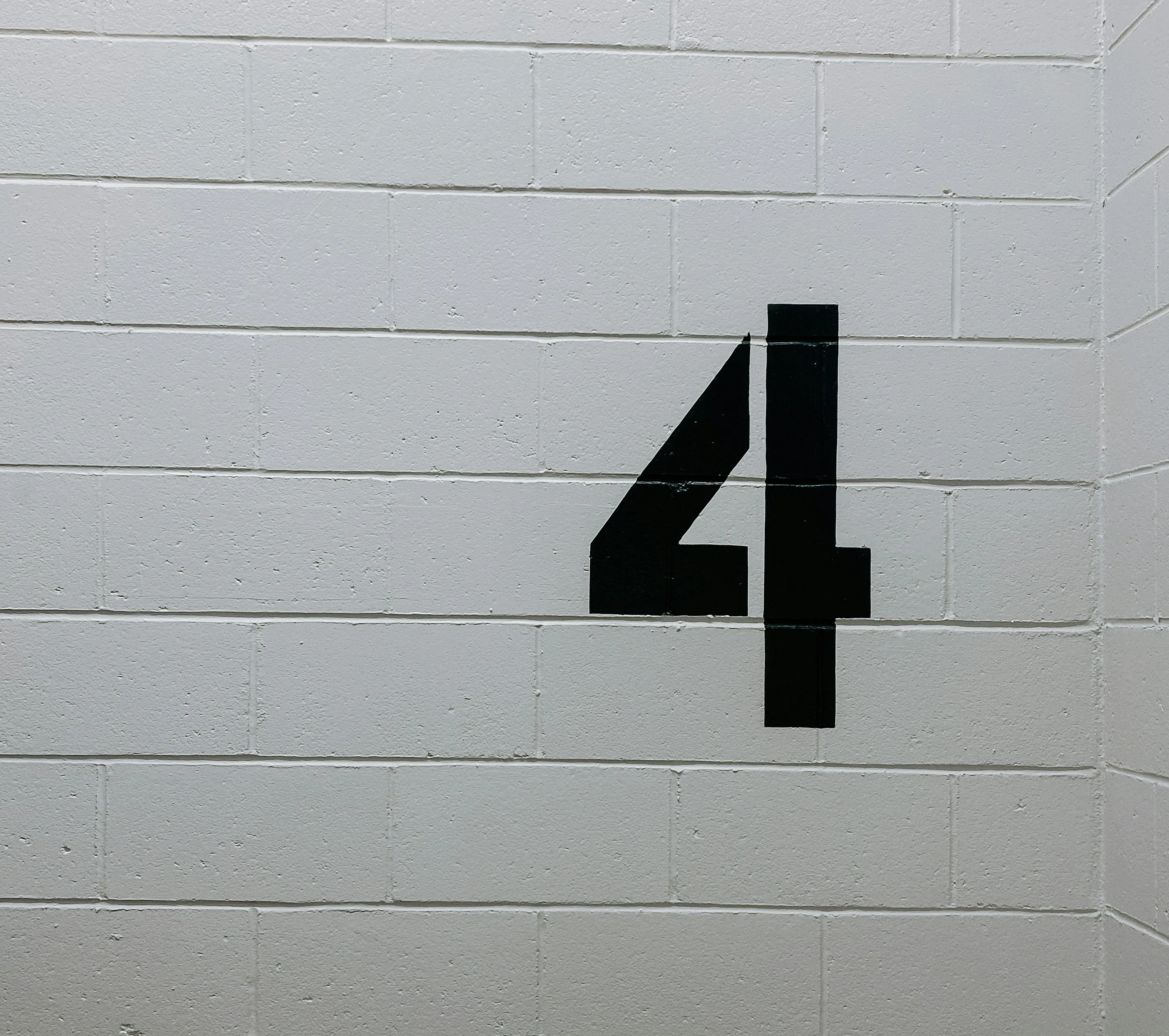 black arrow sign on white brick wall