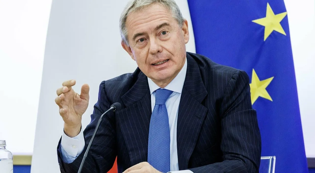 adolfo urso ministro seduto davanti a bandiera europa