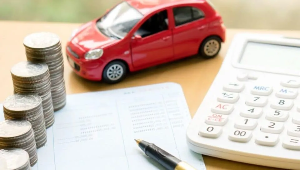 rc auto immagine che ritrae monete, una calcolatrice e un'auto rossa sopra a un foglio e una penna a simboleggiare i costi che bisogna sostenere per l'auto