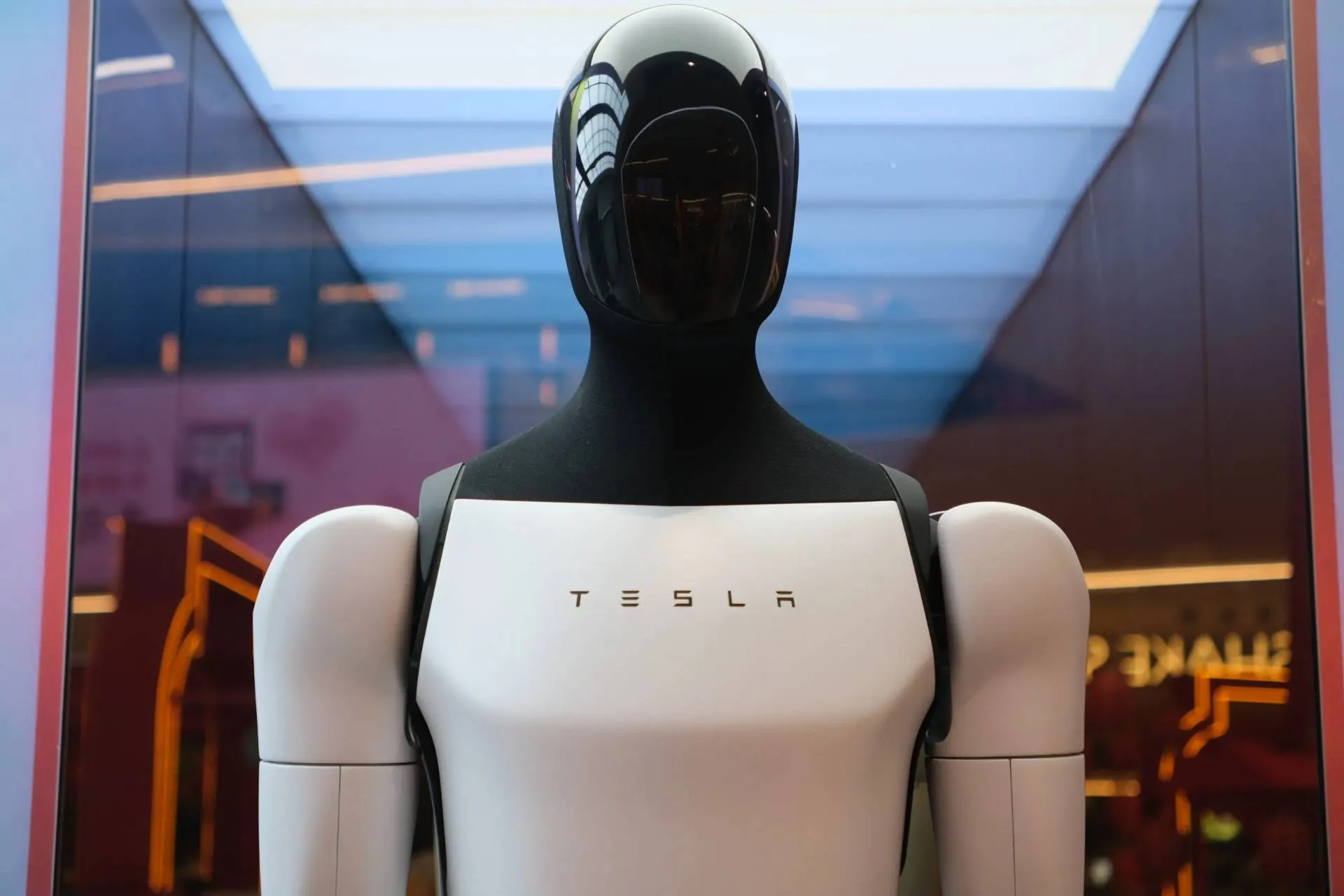 Il robot tesla optimus in primo piano, di colore bianco con testa nera e scritta tesla sul petto