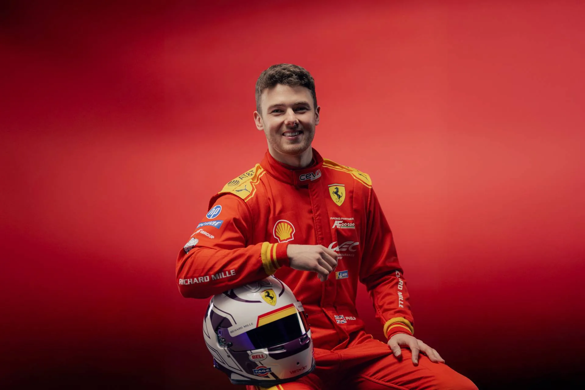 Pilota Ferrari Hanson in tuta rossa con casco bianco