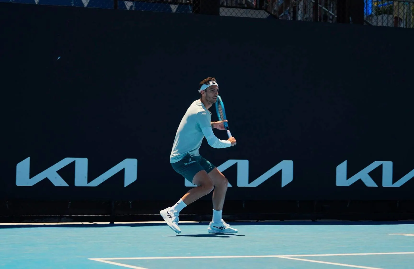 Lorenzo Musetti che gioca a tennis con sfondo la pubblicità di Kia